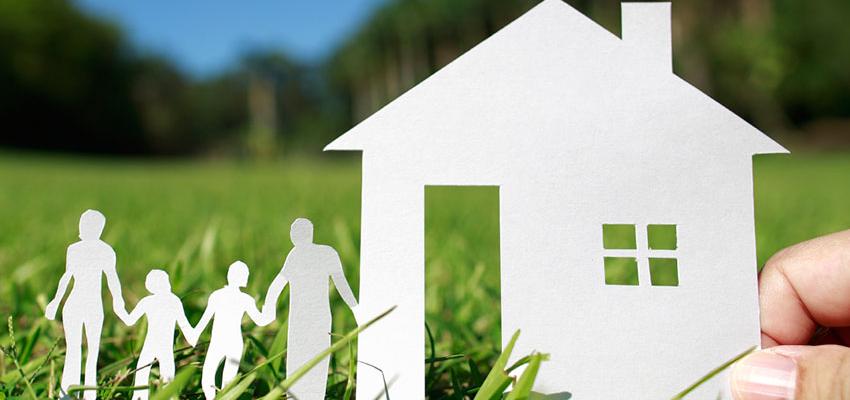 Casa e família recortadas em papel sobre a relva